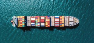 Aerial view of a container ship carrying colorful shipping containers across the ocean.